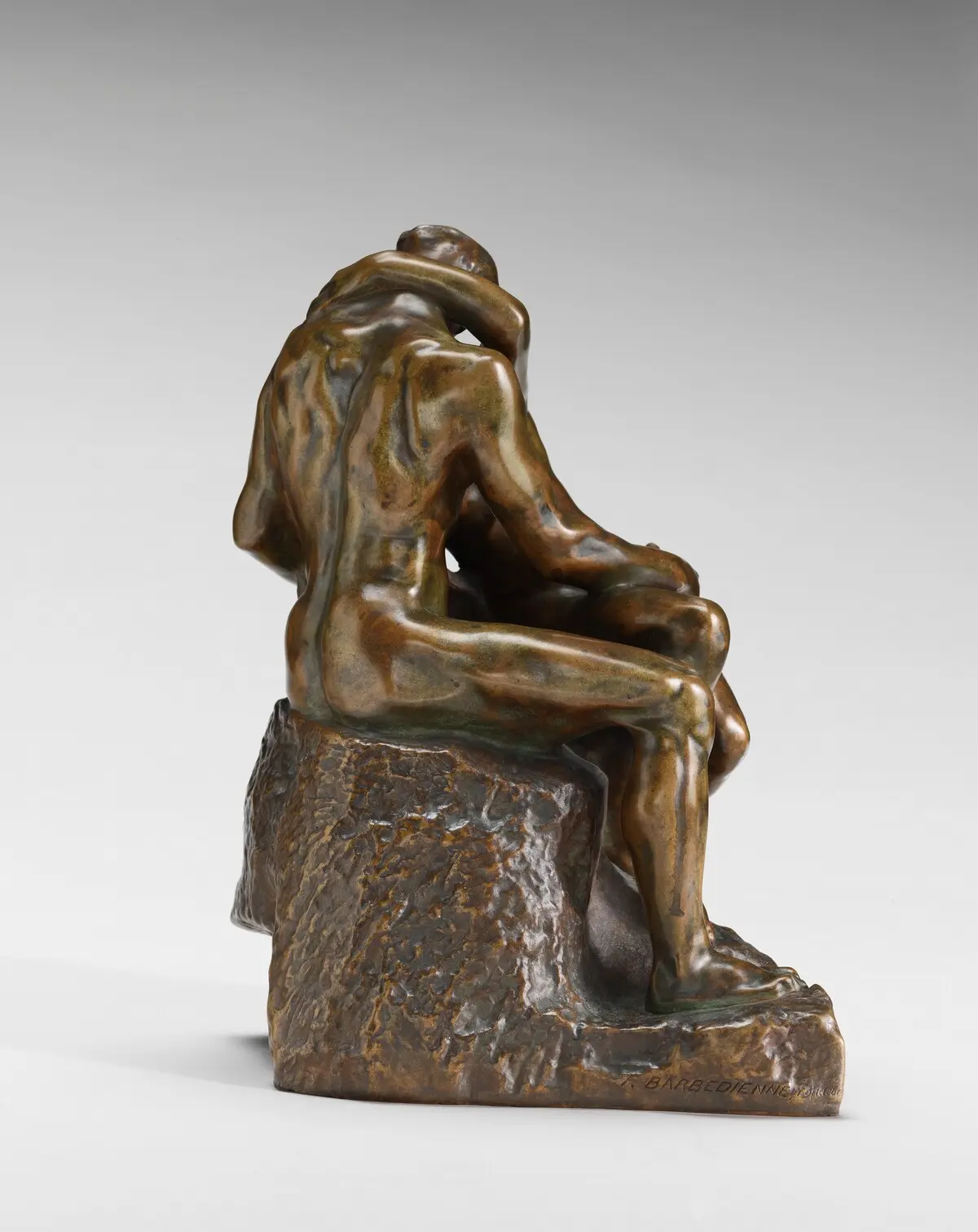 Bronze sculpture of two figures embracing and kissing.